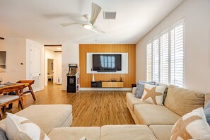 A living room with a television, wooden panel wall, and a ceiling fan.