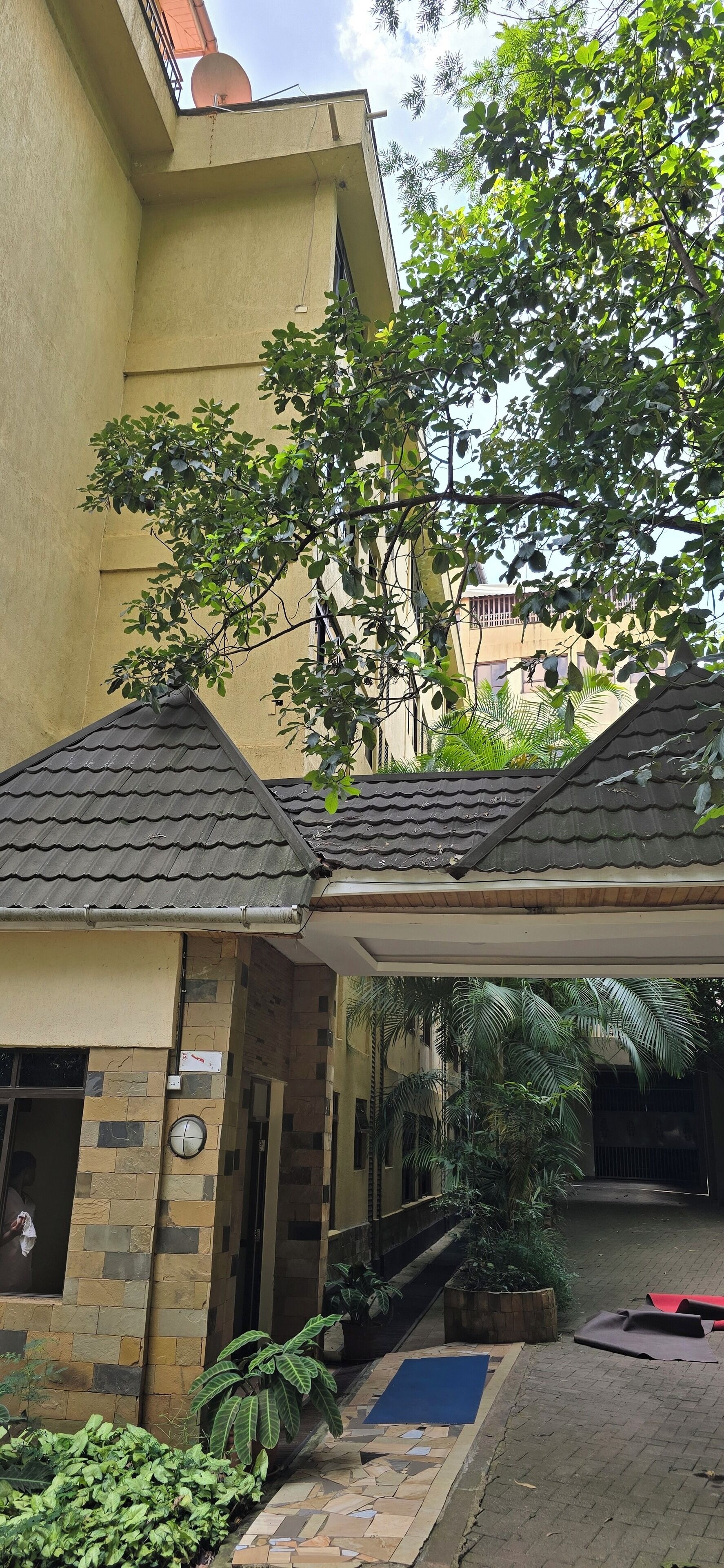 Un edificio con techo de tejas, un patio cubierto y una piscina pequeña.