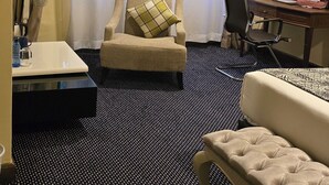 Hotellihuone, jossa on sänky, tuoli, työpöytä ja pieni pöytä.