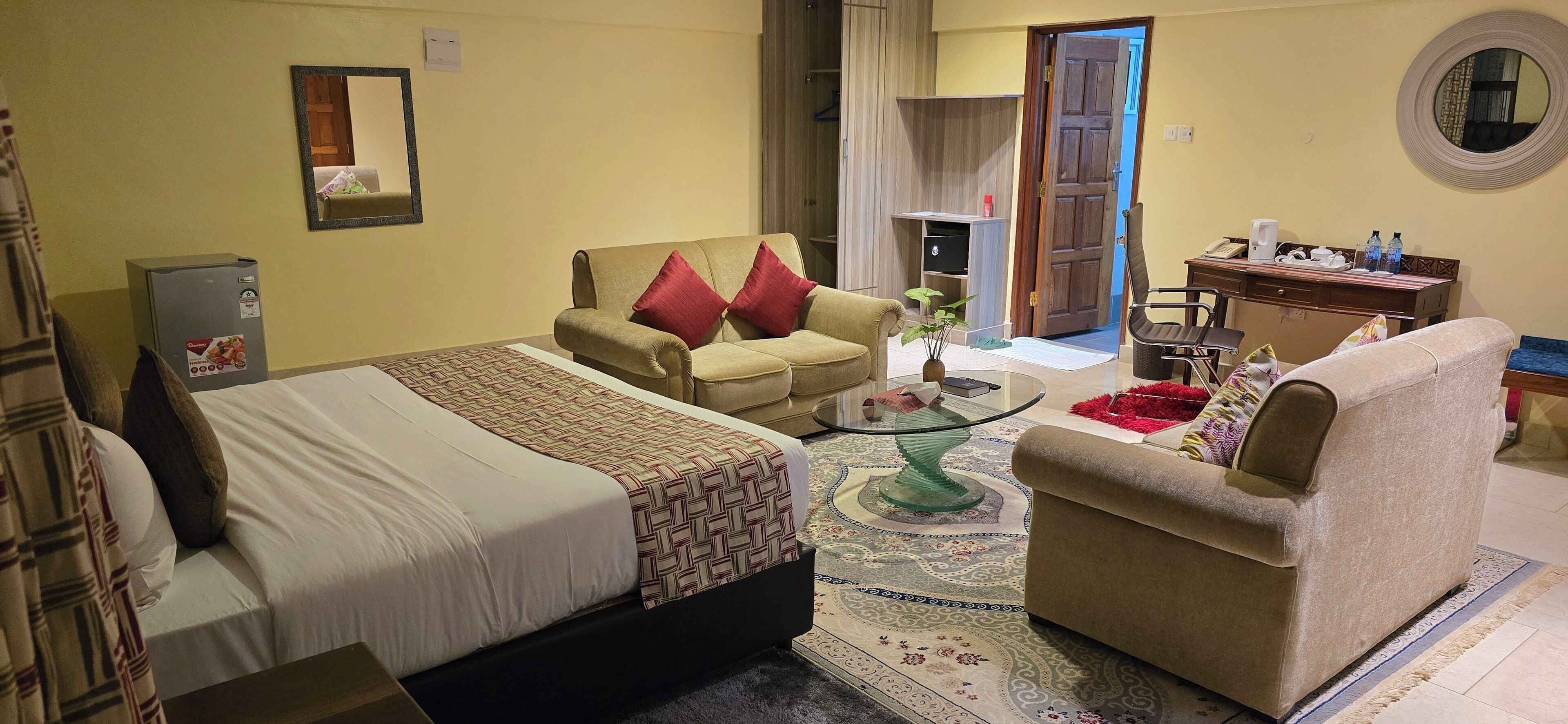 A hotel room with a bed, a sofa, a chair, a desk, and a small table.