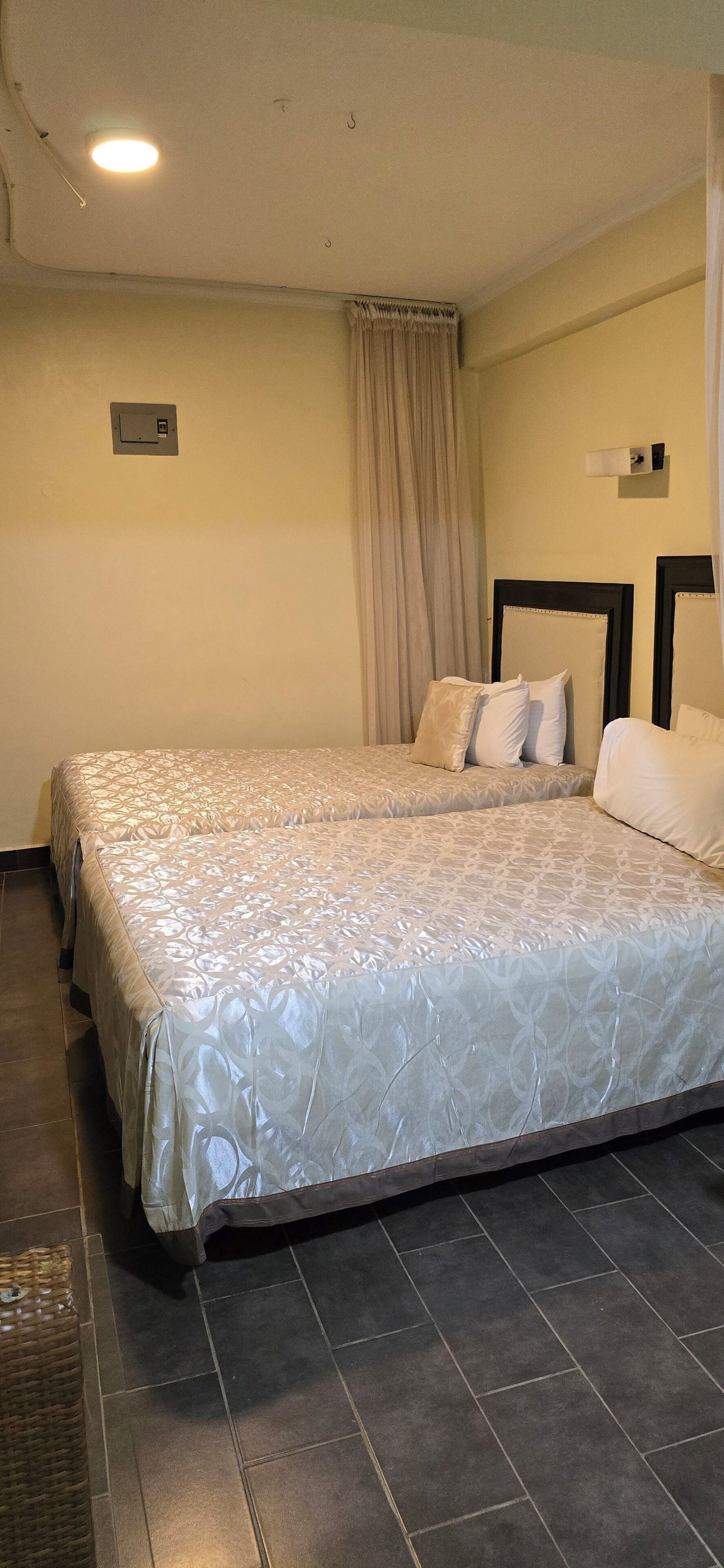 A double bed with a patterned bedspread, a headboard, and a wall-mounted light fixture.