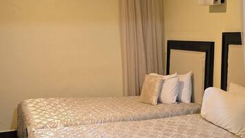 Cama doble con colcha estampada, cabecera y lámpara de pared.