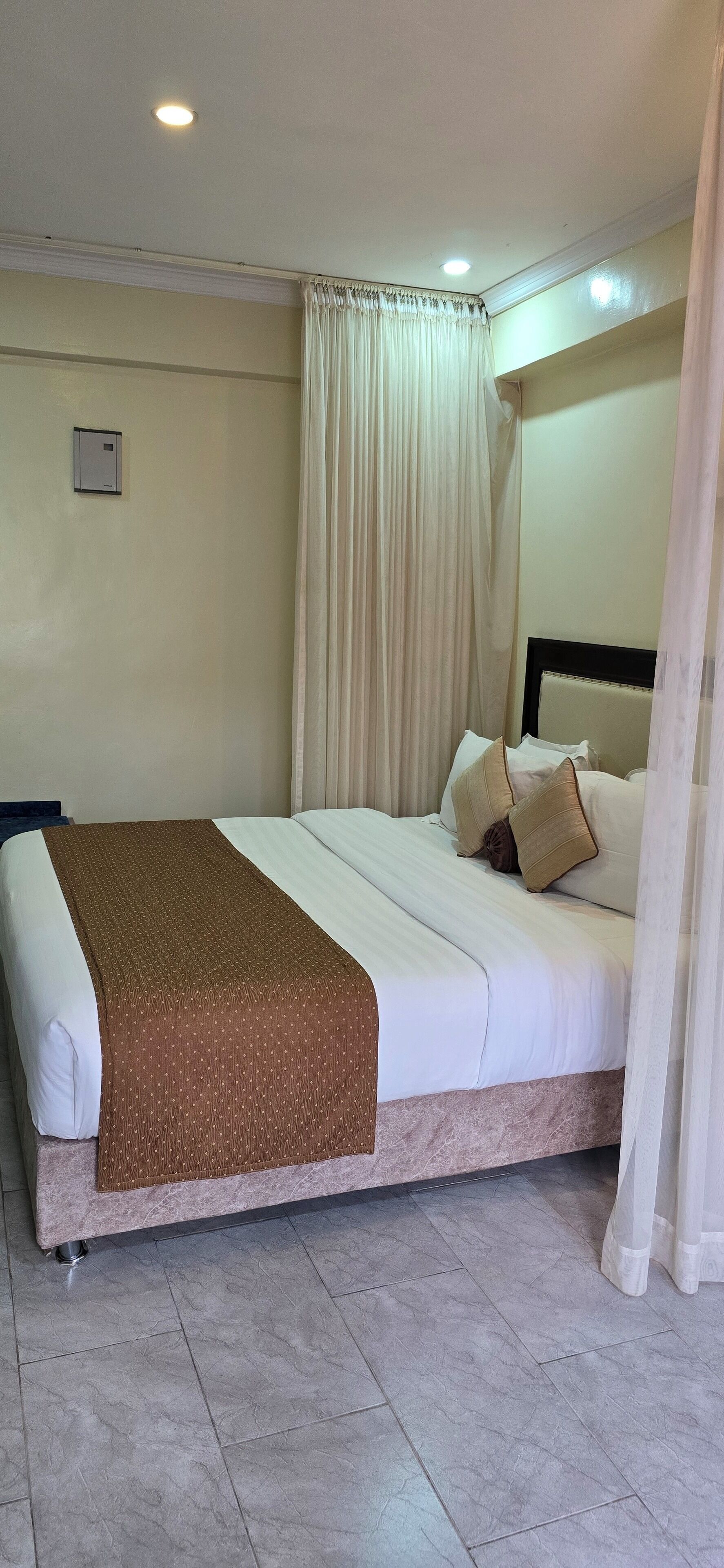 A neatly made bed with a brown blanket, white pillows, and a headboard.