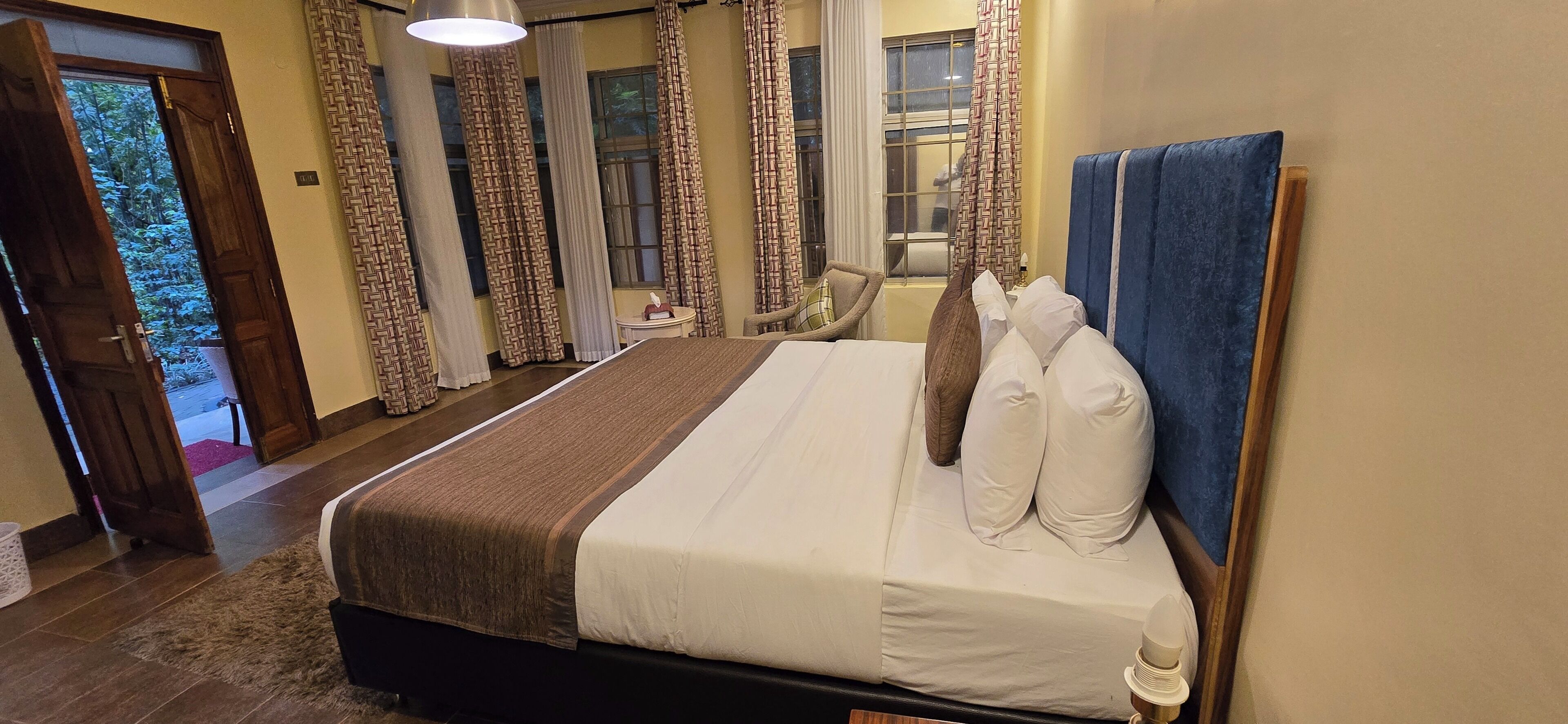 Habitación de hotel con una cama grande, un cabecero de madera y vistas al exterior a través de la ventana.