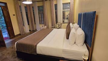 Habitación de hotel con una cama grande, un cabecero de madera y vistas al exterior a través de la ventana.
