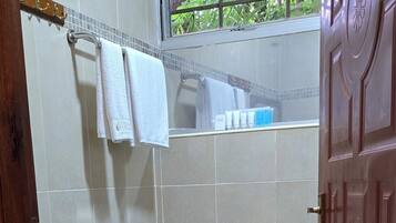 A small bathroom with a toilet, sink, and a window with a view of greenery.