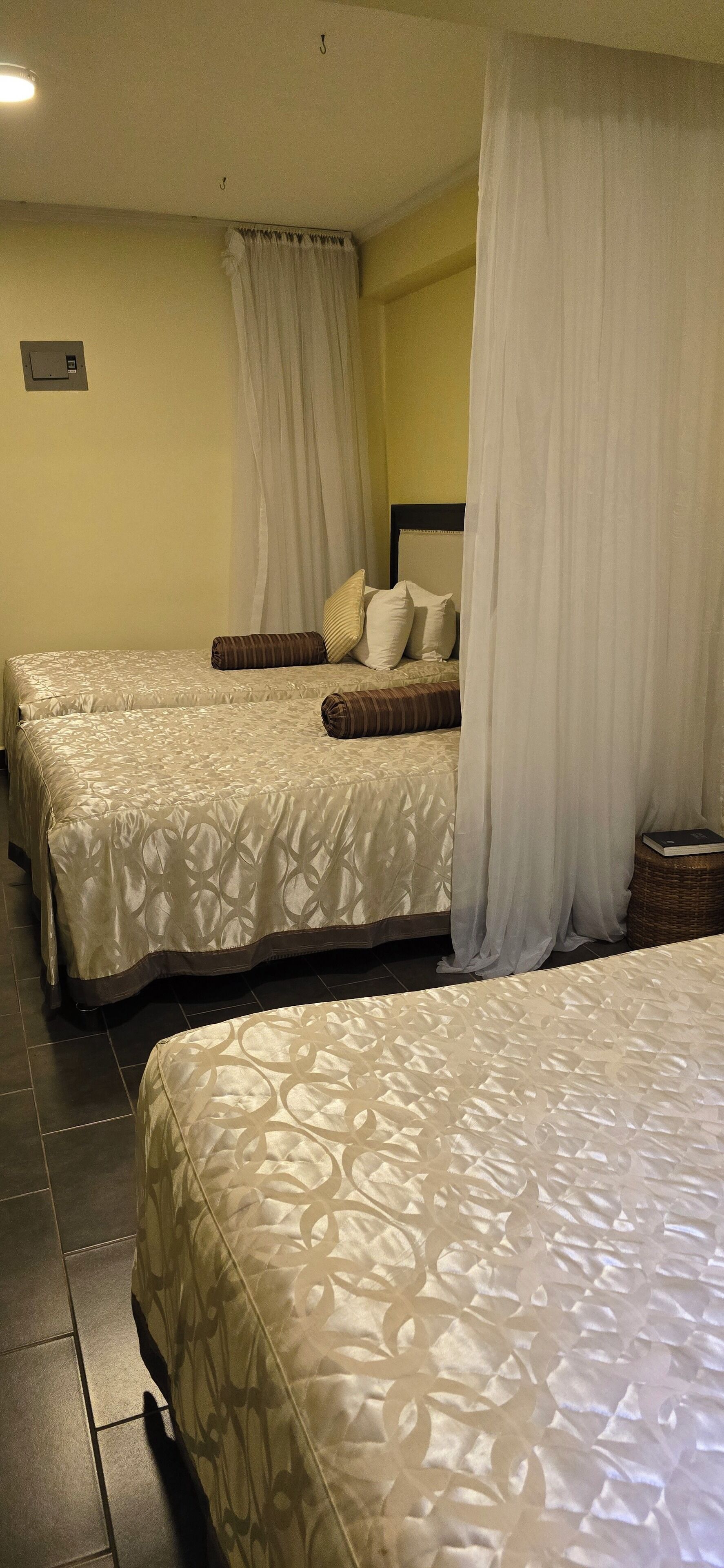 A hotel room with two beds, each with a canopy and patterned bedding.