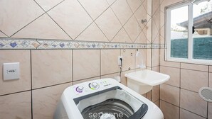 A compact bathroom with a washing machine, a sink, and a window. - Apts in Condominium 40 Meters From Bombinhas Beach - Bdss (Bombinhas)