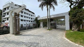 Entrada de un edificio con pavimento de baldosas hexagonales, una palmera y un letrero que dice 'Solar Das Bromelias'.