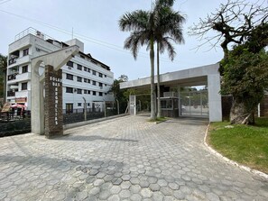 A building with a modern entrance, a sign reading "Solar Das Bromelias", and a paved hexagonal tile ground. - Apts in Condominium 40 Meters From Bombinhas Beach - Bdss (Bombinhas)