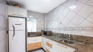 Een keuken met witte kasten, een inbouwkoelkast, een magnetron en een spoelbak.