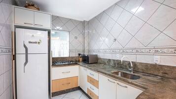 A kitchen with white cabinets, a built-in refrigerator, a microwave, and a sink.