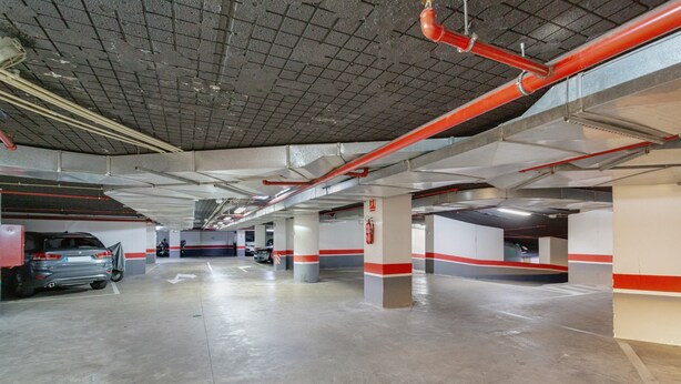 Eine mehrstöckige Parkgarage mit Betonböden und roten und weißen Säulen.