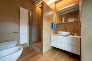 A modern bathroom with a glass shower enclosure, a white sink with a bowl, and a mirror above the vanity.