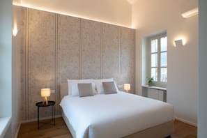 Ein Schlafzimmer mit einem großen Bett, zwei Nachttischen mit Lampen, einem Fenster mit Blick und einer Heizung.