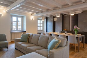 A modern living room with a sofa, dining table, and chairs. There is a window with a view of buildings outside. - On My Way Loft-Central Rooftop Apt with AC/Terrace (Como)