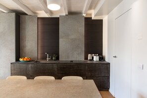A modern kitchen with a built-in island, dark cabinetry, and a white door. - On My Way Loft-Central Rooftop Apt with AC/Terrace (Como)