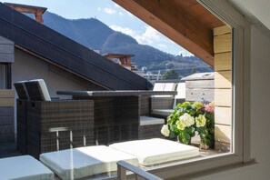 A rooftop terrace with wicker furniture, a view of mountains, and a flower arrangement. - On My Way Loft-Central Rooftop Apt with AC/Terrace (Como)