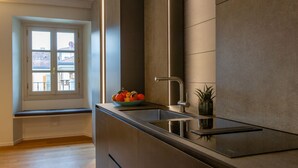 Una cocina moderna con estufa integrada, un lavamanos y una ventana con vista a un área residencial.