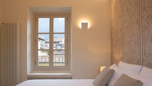Un dormitorio con cama, ventana, radiador y una lámpara fijada a la pared.