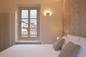 Ein Schlafzimmer mit Bett, Fenster, Heizkörper und einer Wandleuchte.