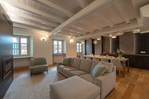 A modern living room with a sectional sofa, a dining table, and a kitchen area.