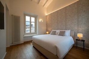 A bedroom with a large bed, a radiator, a window, and a wall with a floral pattern.