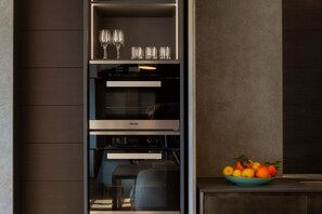 A modern kitchen with a built-in oven, a microwave, and a glass-fronted wine cabinet. - On My Way Loft-Central Rooftop Apt with AC/Terrace (Como)