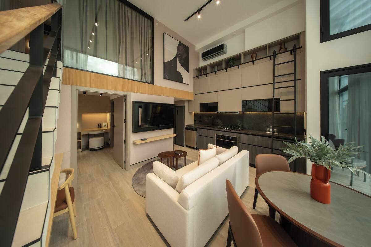 Un appartement moderne comprenant un espace de vie, un coin repas, une cuisine et un escalier menant à un niveau supérieur.