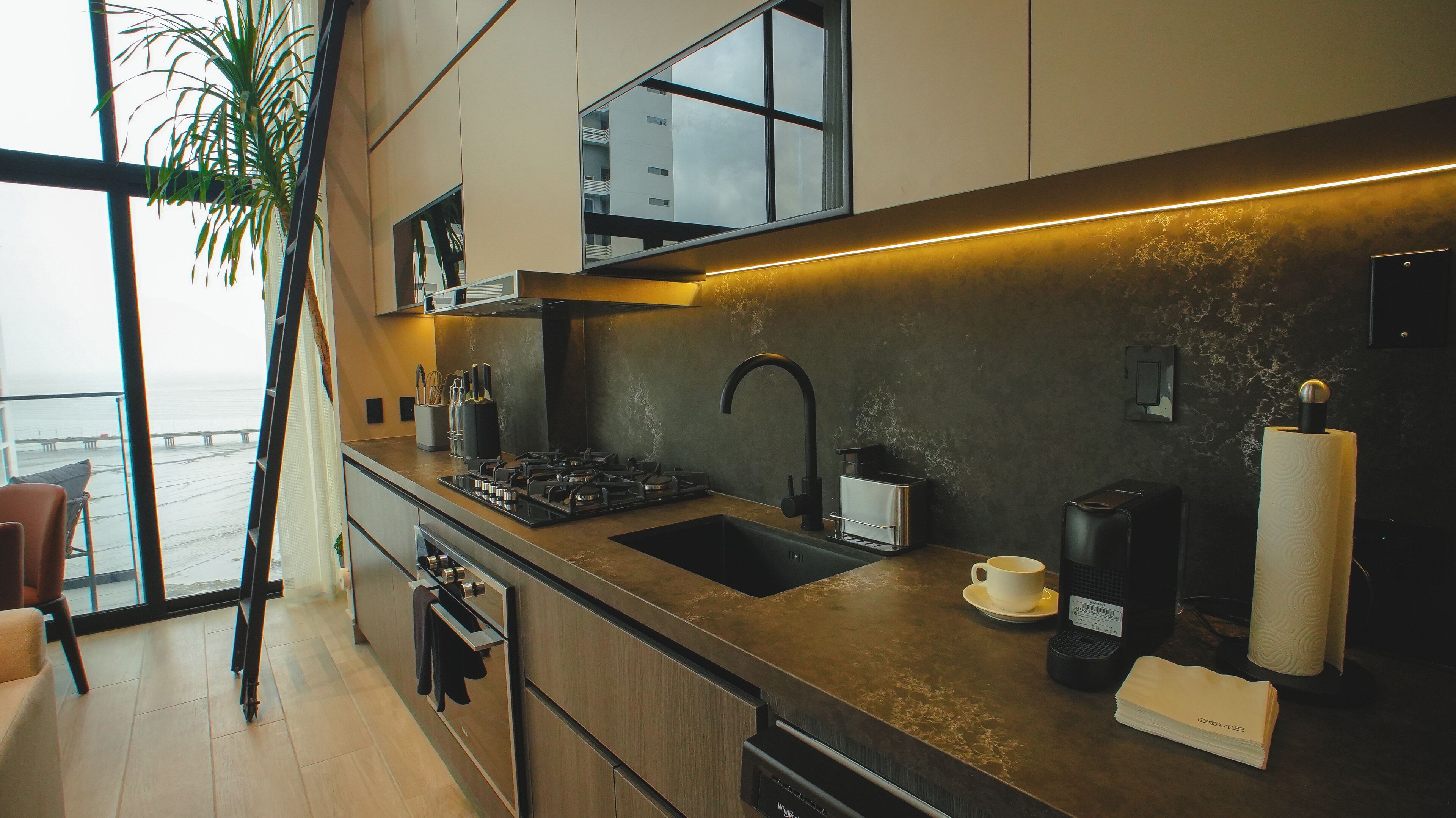 Una cocina moderna con un ventanal grande, electrodomésticos de acero inoxidable y vistas al mar.
