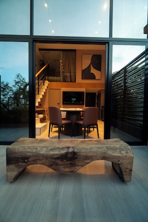 Un intérieur moderne avec un banc en bois, un coin repas avec des chaises, un escalier et une grande fenêtre.
