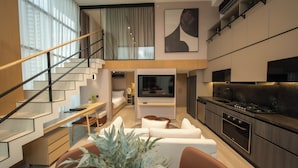 Een modern appartement met een zithoek, keuken en een trap naar een hoger niveau.