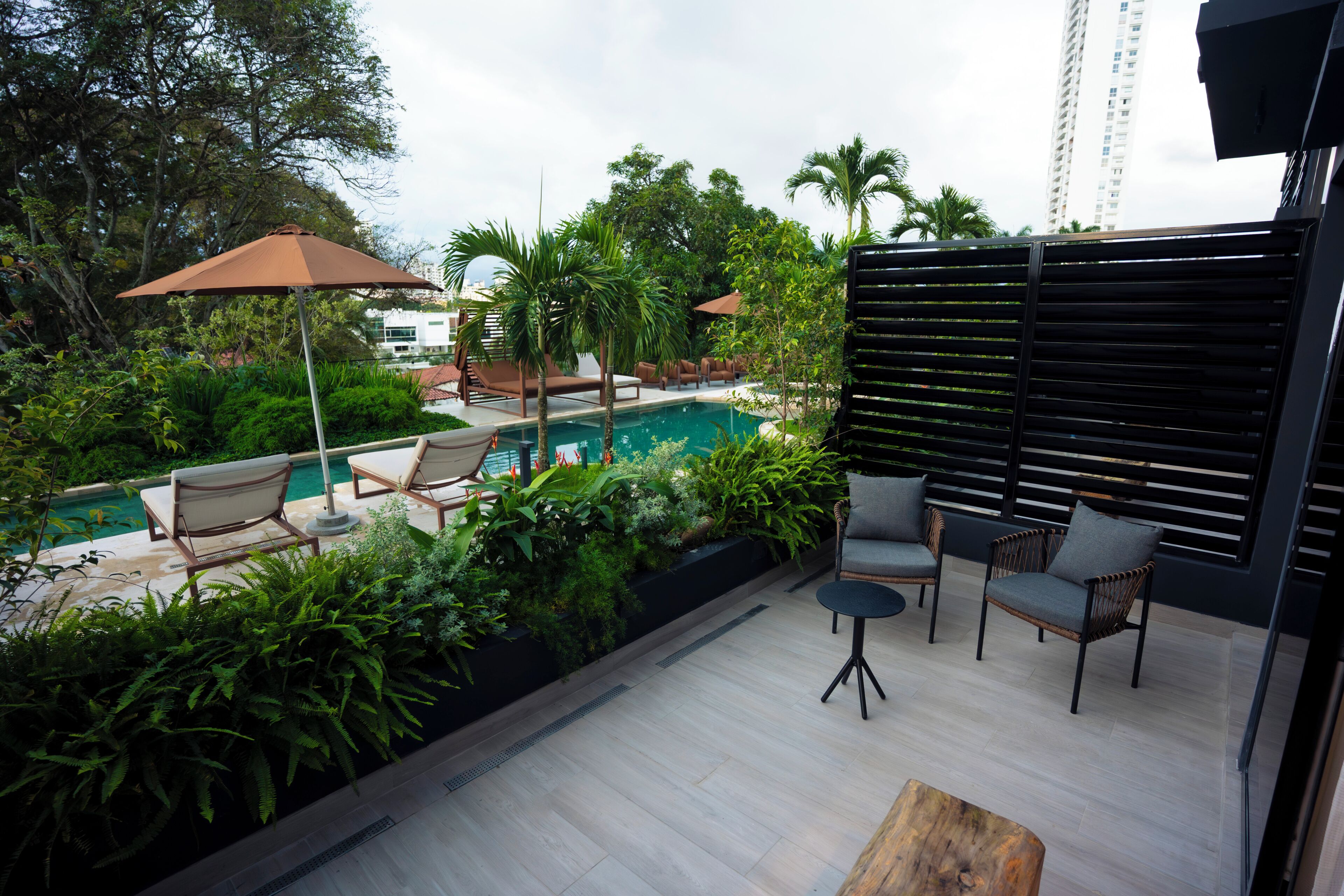 A poolside area with lounge chairs, a small table, and a wooden bench.