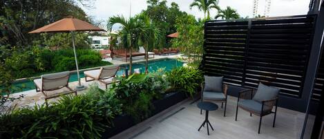 A poolside area with lounge chairs, a small table, and a wooden bench.