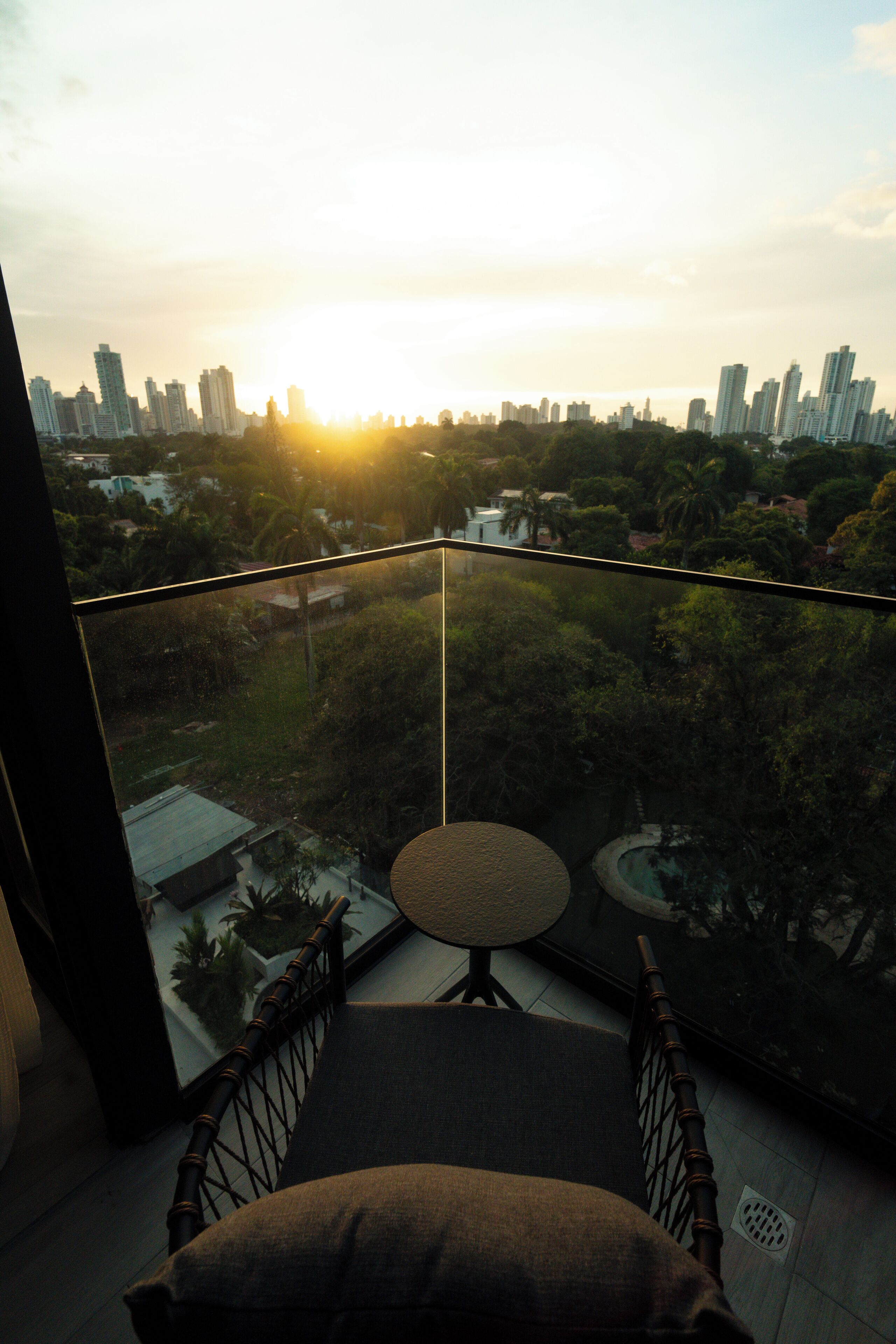 A balcony with a view of a cityscape and greenery.