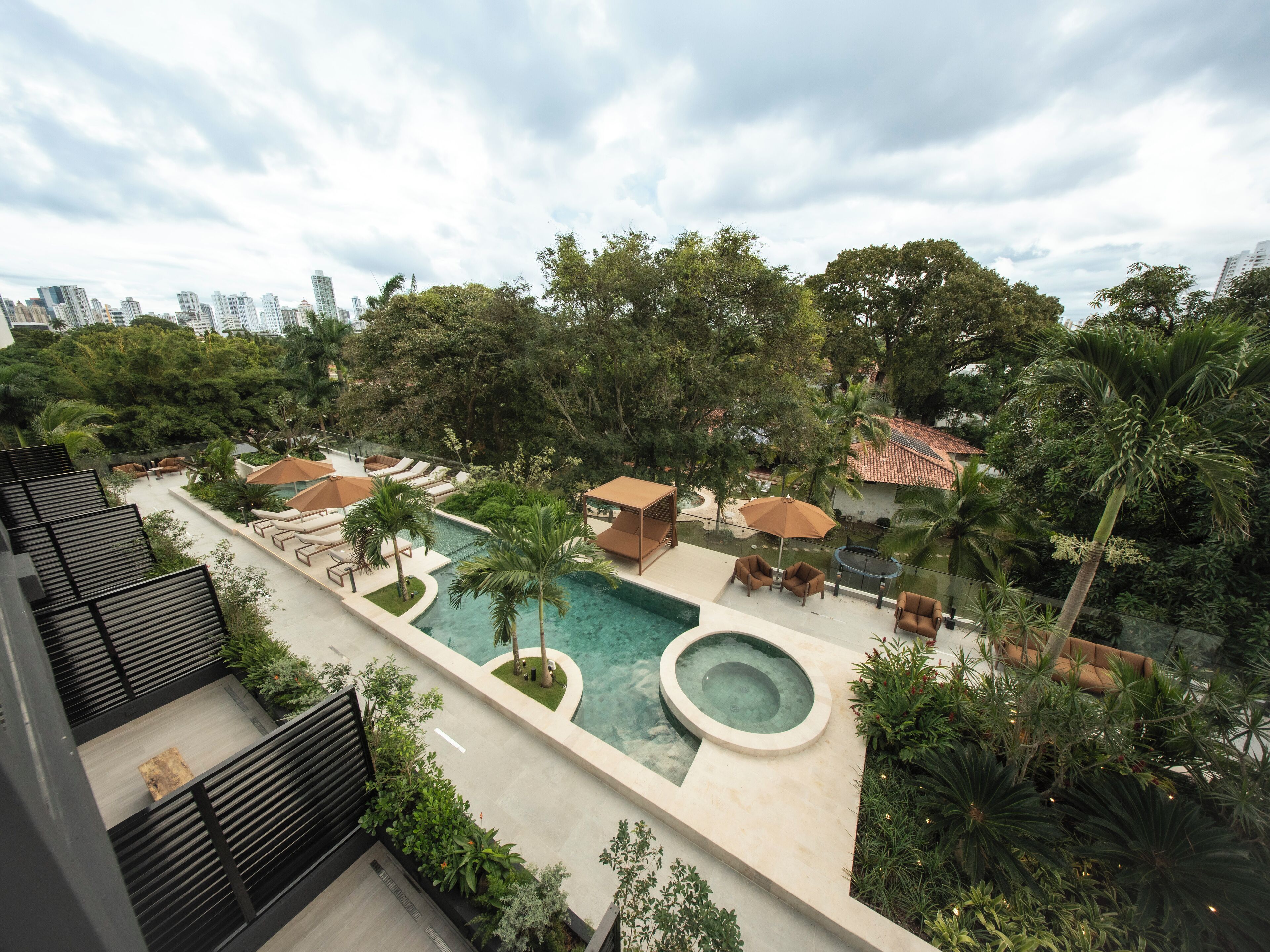 A rooftop pool area with lounge chairs, umbrellas, and a hot tub.