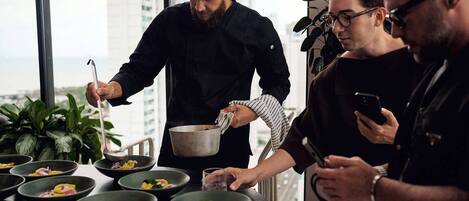 A group of people in a modern kitchen with a city view, preparing food.