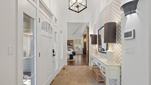 A hallway with white doors, a wooden bench, and patterned wallpaper. - Grand Beach 4BR Pool House with Private Pool, Golf Cart & Fireplace (New Buffalo)