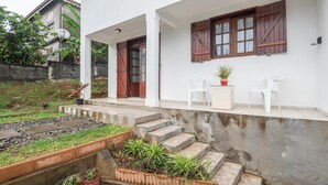 A white building with a porch, steps, and potted plants.