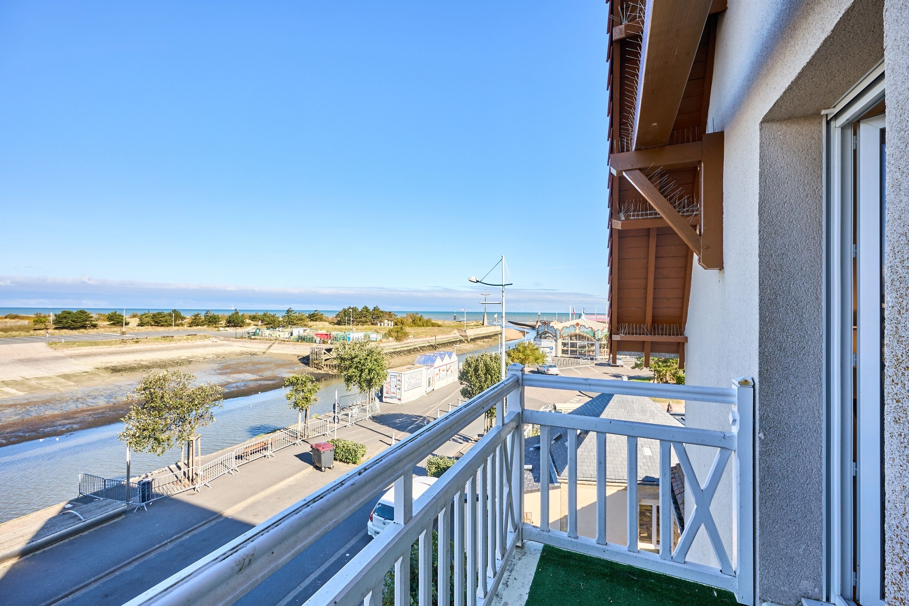A balcony with a view of a coastal road and a clear sky.