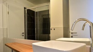 A bathroom with a wooden vanity, a white sink, and a glass shower enclosure. - Golden B&B (Split)