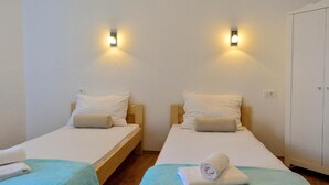 Two single beds with wooden frames and white bedding, each with a wall-mounted light fixture. - Golden B&B (Split)