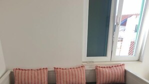 A white sofa with three striped pillows, a black cushion, and two drawers. - Golden B&B (Split)