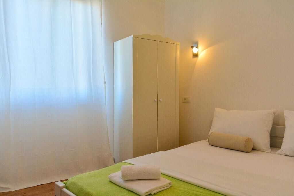 A hotel room with a bed, a wardrobe, and a wall-mounted light.