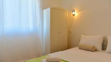 A hotel room with a bed, a wardrobe, and a wall-mounted light.