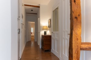 Ein Flur mit Holzdielen, weißen Türen und einer Holzbalkenkonstruktion.