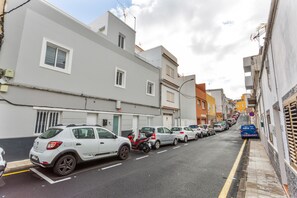 A narrow urban street lined with parked cars and buildings.