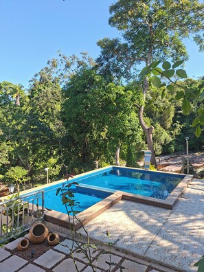 Une piscine rectangulaire à l’eau d’un bleu limpide, entourée d’une terrasse carrelée et bordée d’une rambarde en métal.