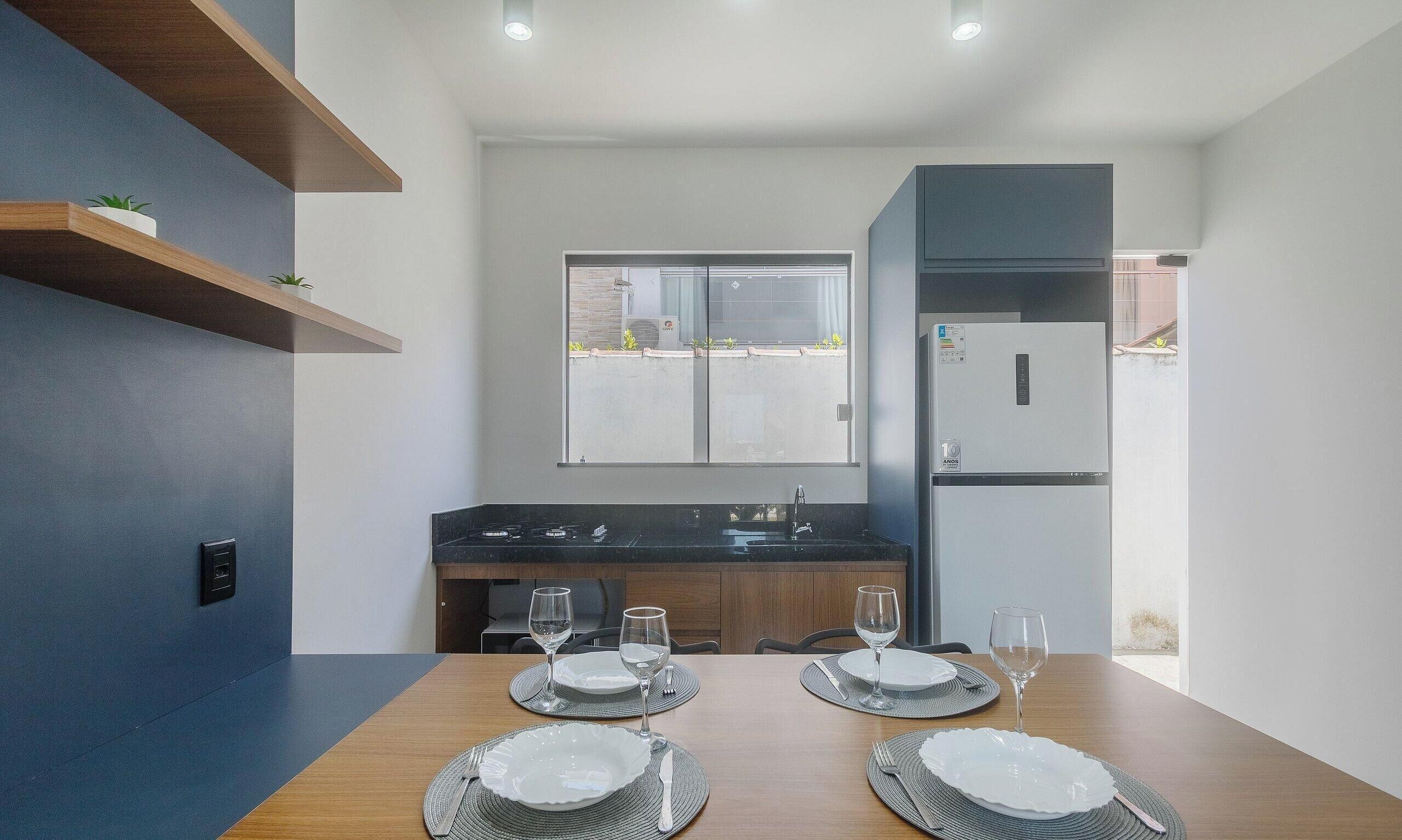 A modern kitchen with a dining table set for two, a built-in oven, and a refrigerator.