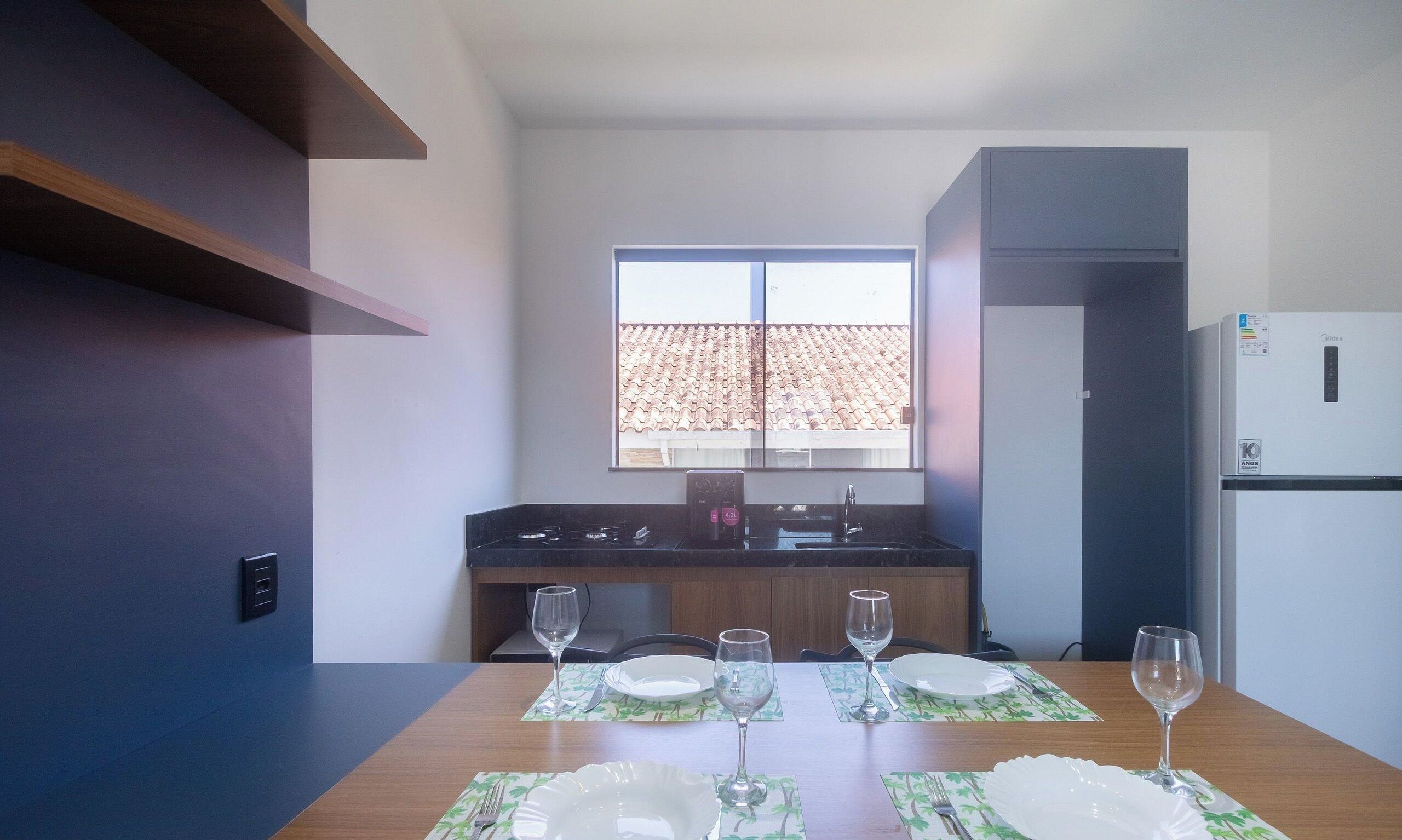 Una cucina moderna con una finestra, un frigorifero e un tavolo da pranzo apparecchiato con piatti e bicchieri.